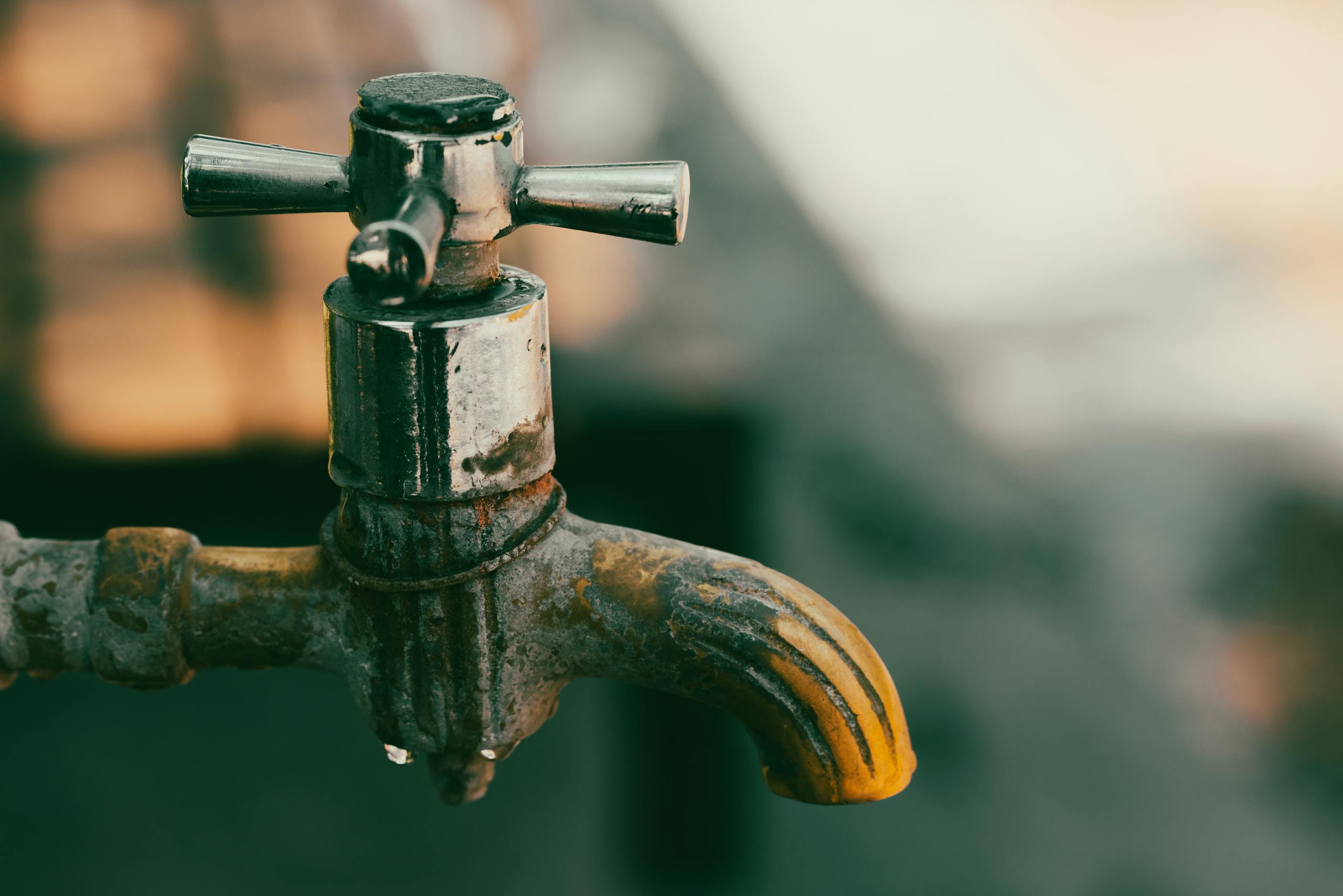 Detailed close-up of a rustic metal faucet with water droplets, perfect for concepts of conservation and decay.