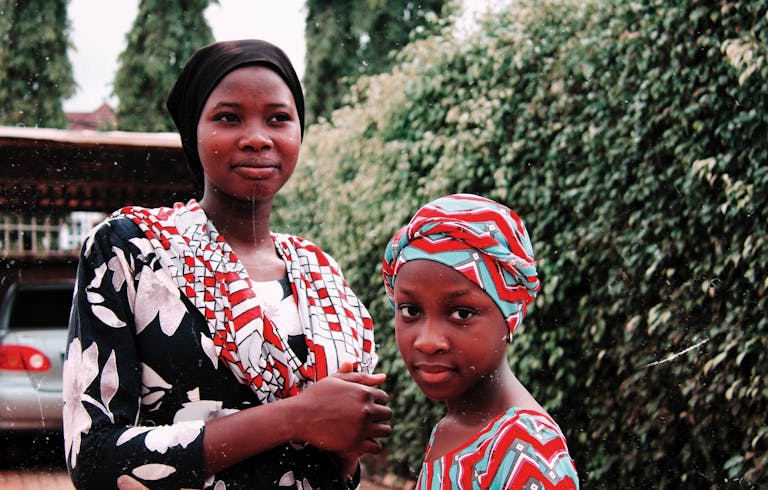 Beautiful portrait of two African sisters in traditional attire, outdoors.